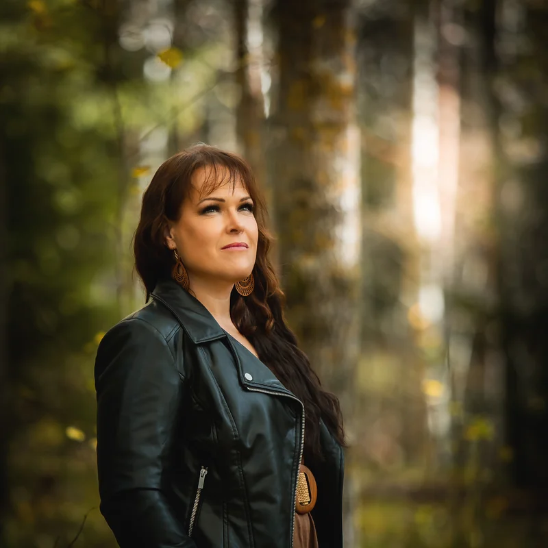 Anne Simonen seisoo metsässä iltavalossa